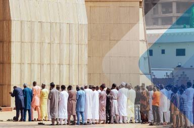 Fila de hombres ante una mezquita de Abuja para ilustrar un artículo sobre EOR en Nigeria. Foto de Habila Masawaje